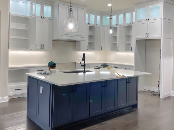 Modern Kitchen renovation in McKinney with white cabinetry, blue island, glass front uppers cabinet doors and pendant lighting.